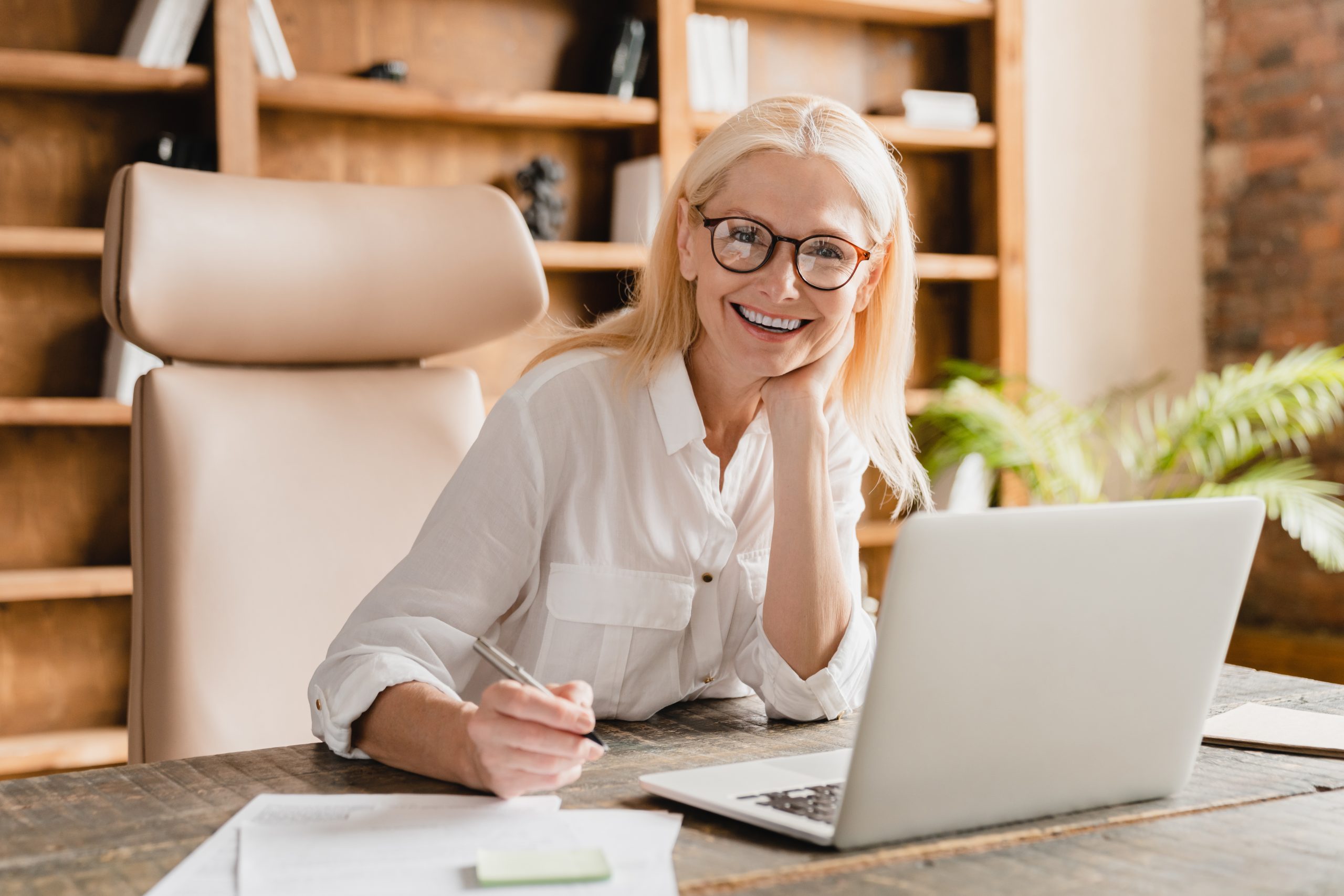 Freelancer teacher doing paperwork, signing contracts, documents while working on laptop in office