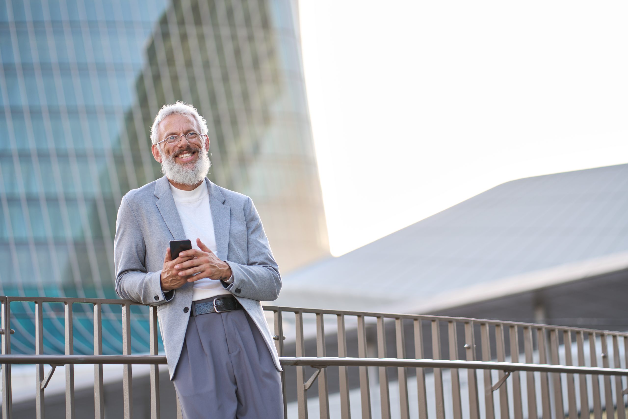 Happy old professional business man holding smartphone using cell phone outside.