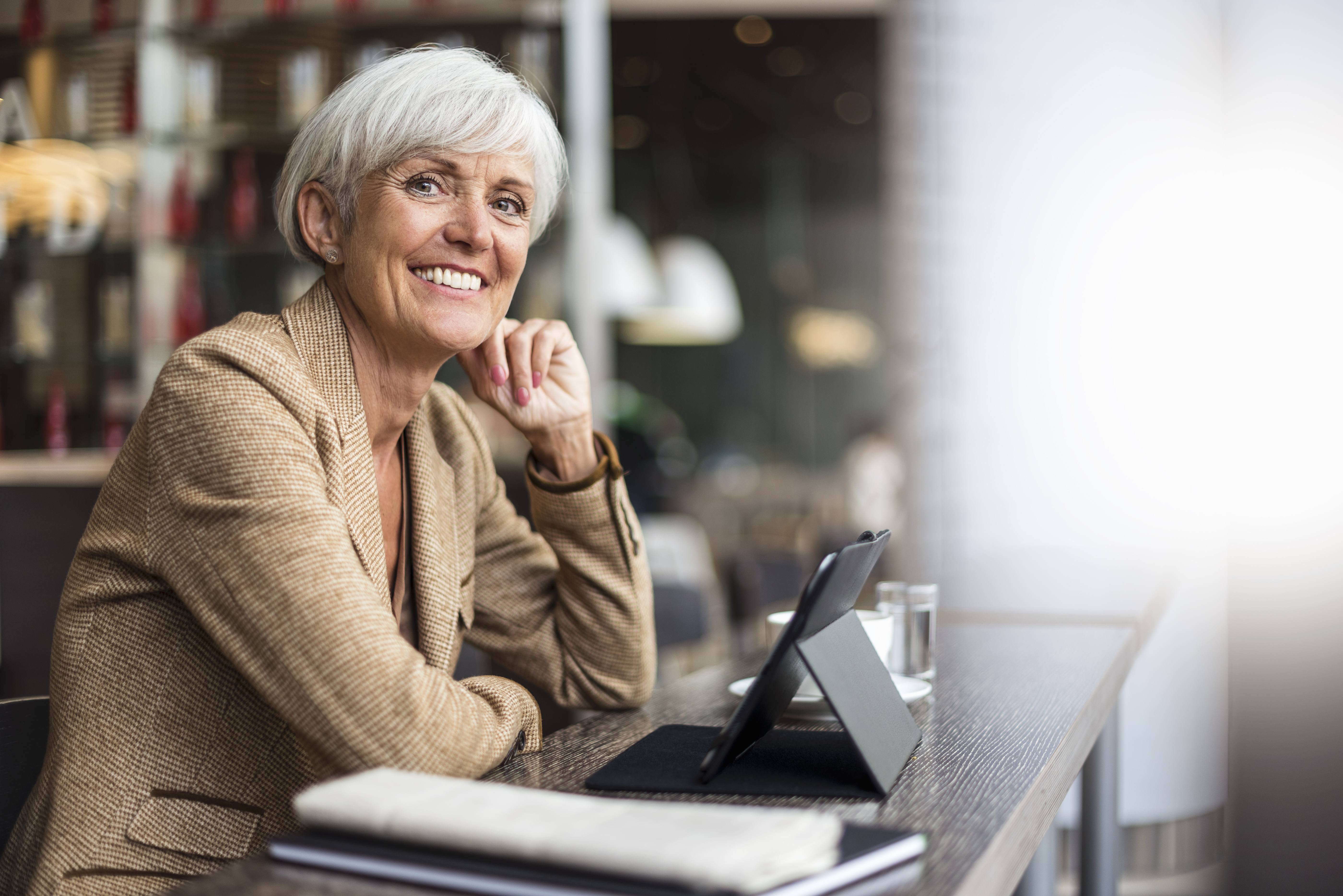 Portrait of smiling senior businesswoman with tablet in a cafe