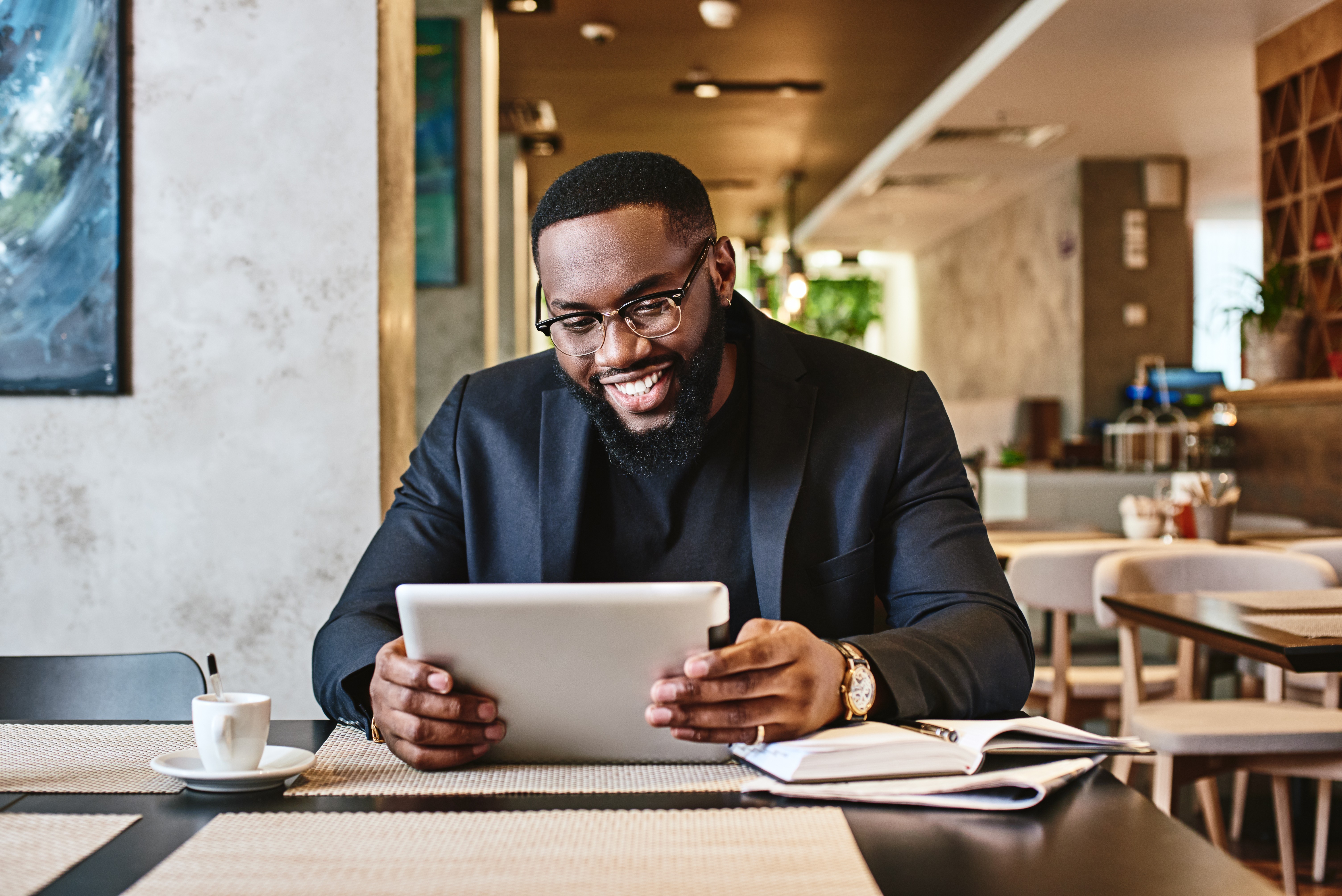 Shot of a young afro american businessman using tablet while resting in the cafe