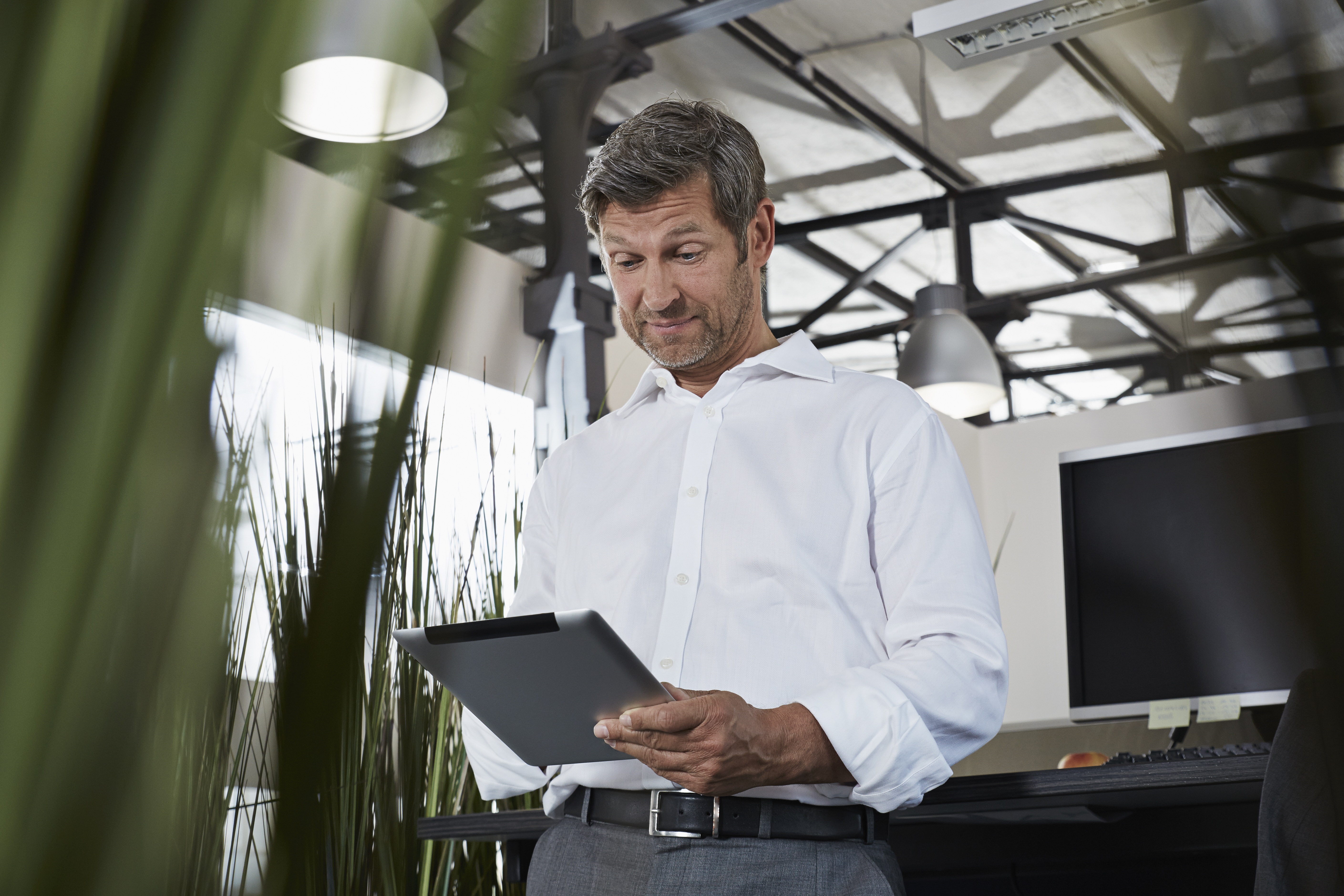 Surprised businessman in office looking at digital tablet