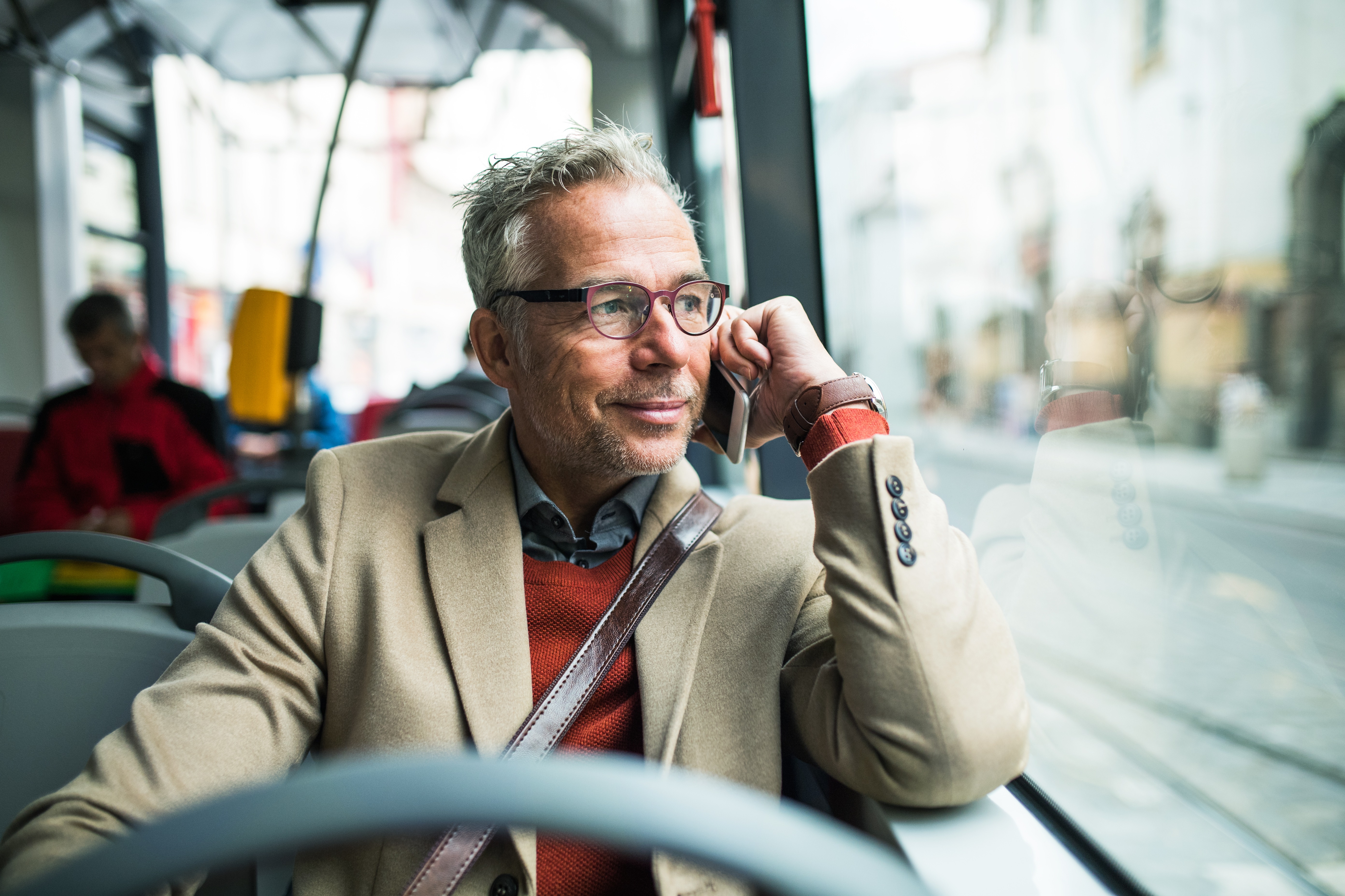 Tired mature businessman travelling by bus in city.